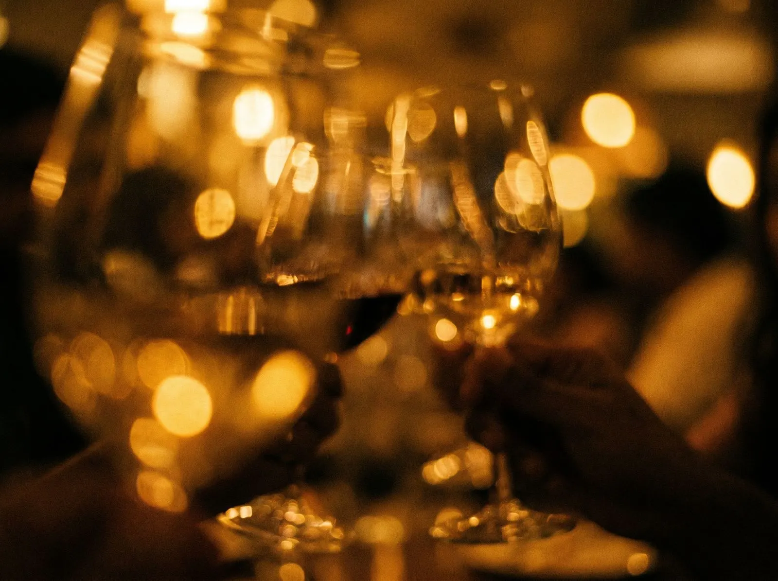 Warm bokeh and wine glasses, dim restaurant